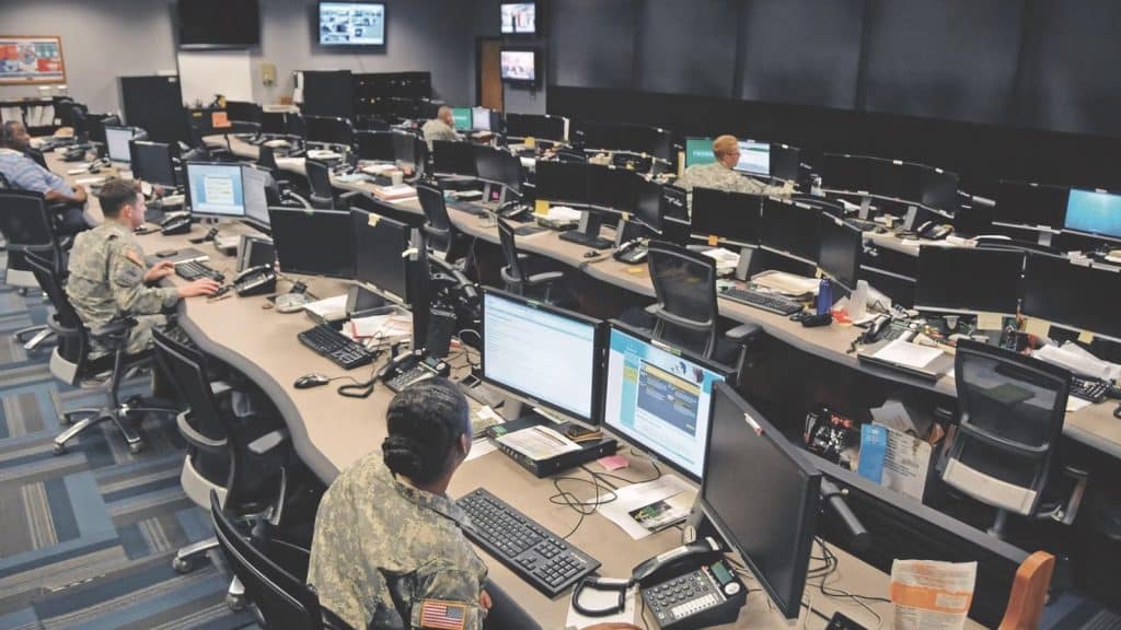 American soldiers behind a lot of computer in big desk room